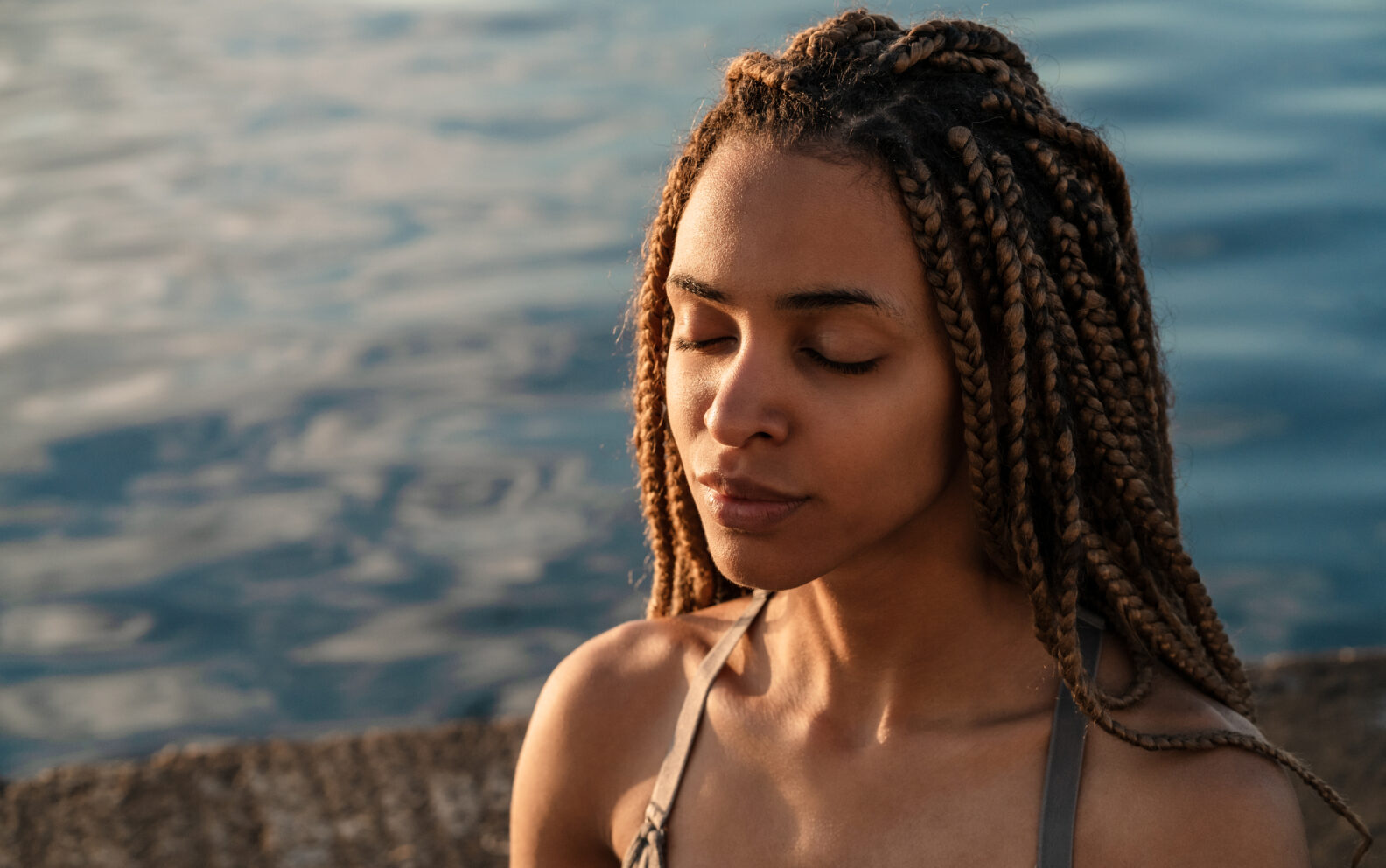African woman practicing yoga meditation at the beach