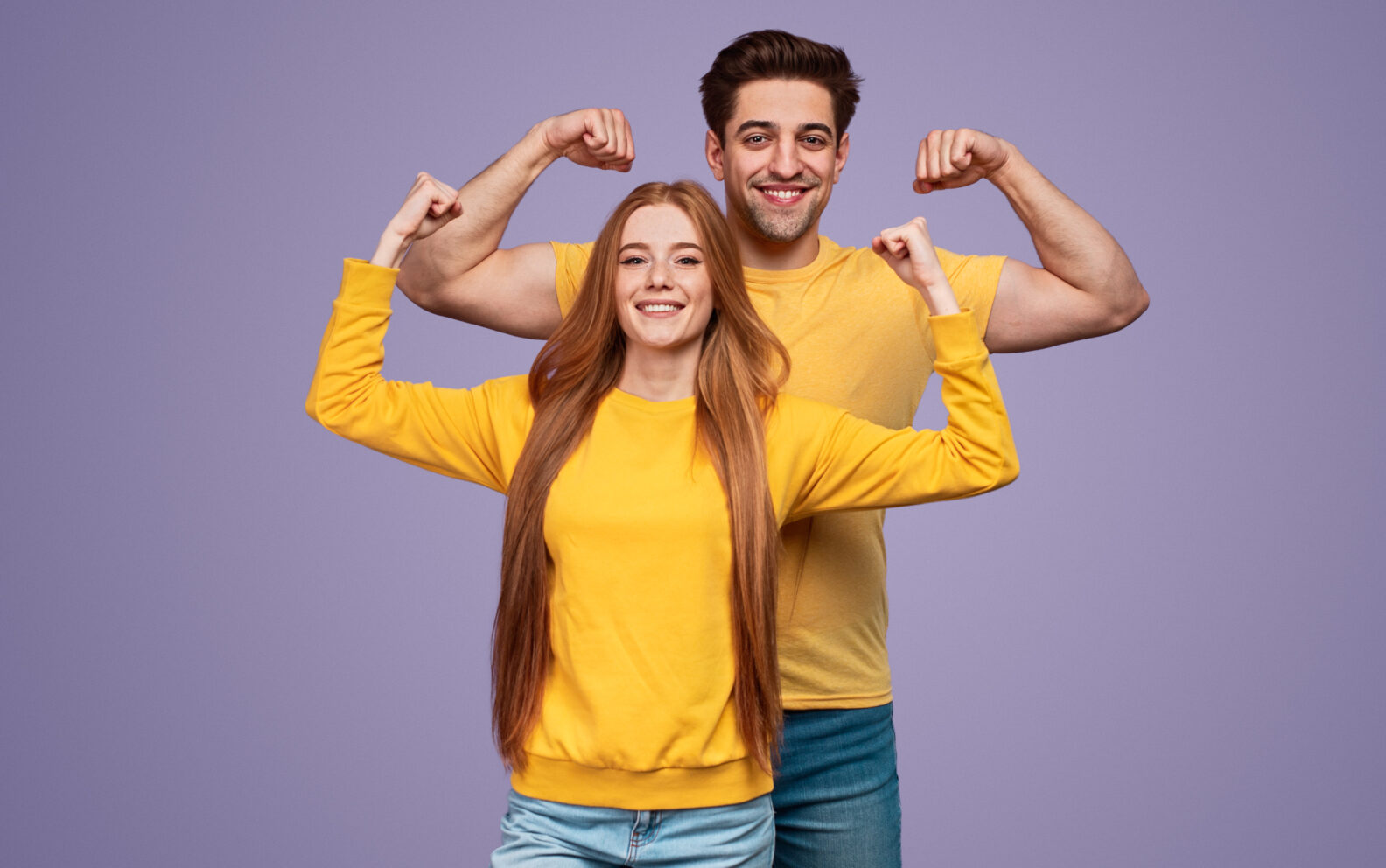 Cheerful young couple flexing muscles