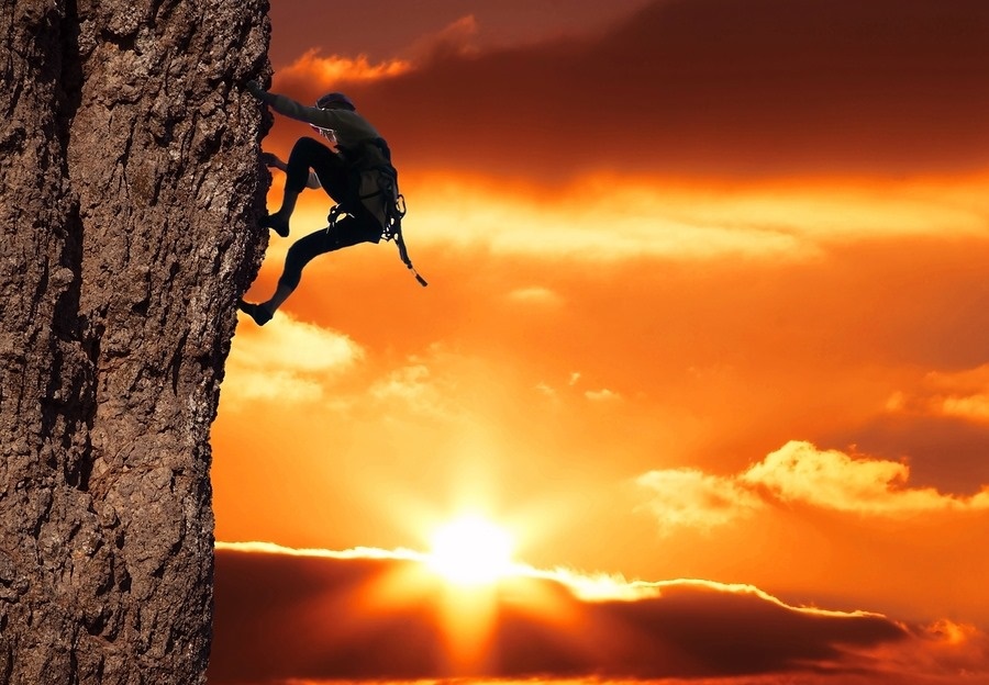 girl climbing on the rock on sunset background